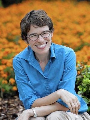 Woman in a blue shirt and khaki pants in front of a field of orange wildflowers